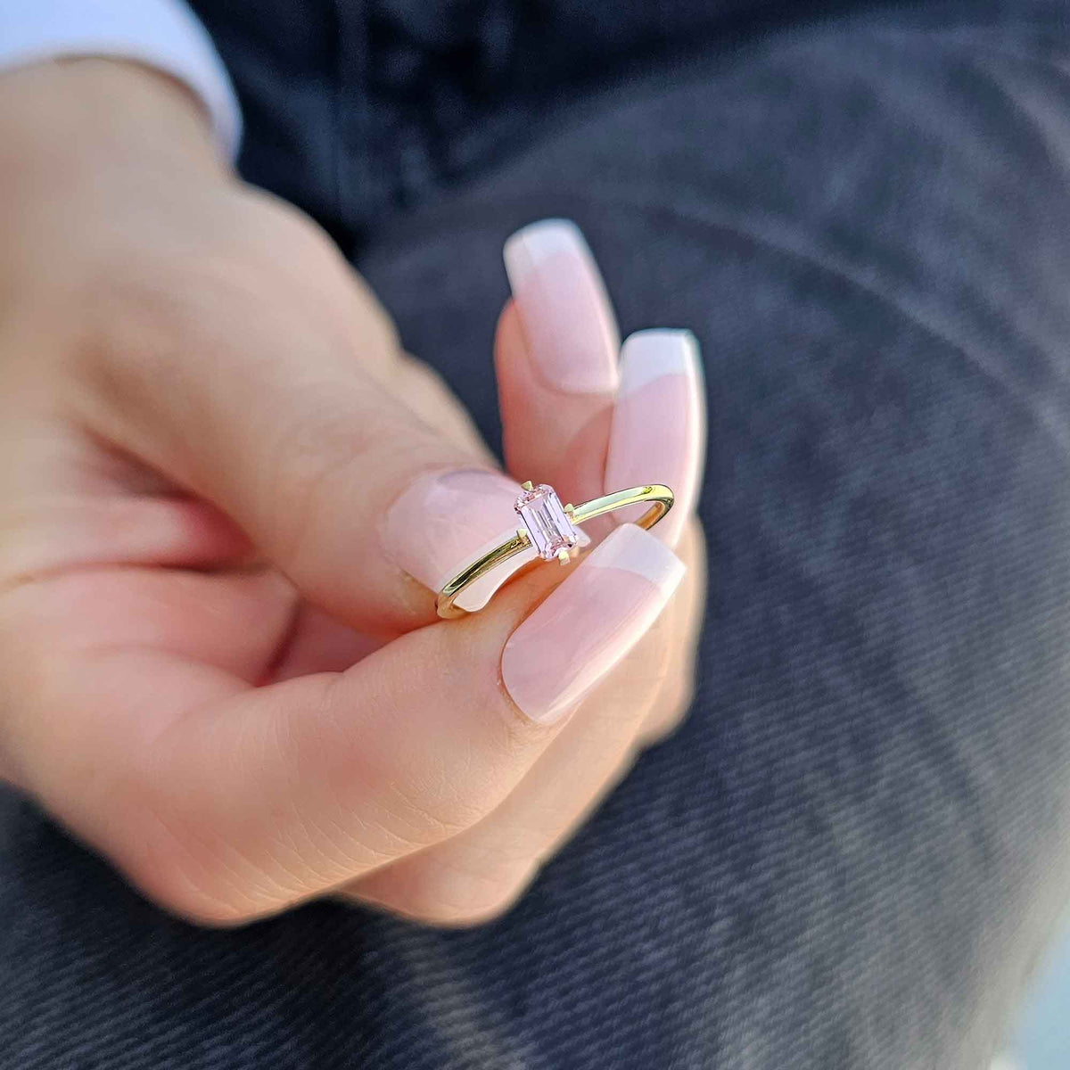 Gold pink-stone baguette solitaire ring worn on hand, side view